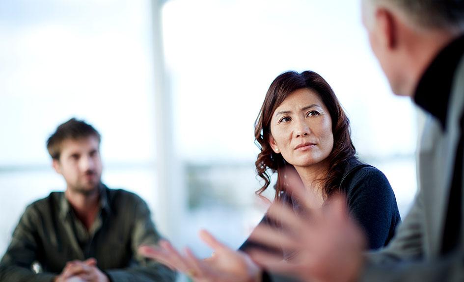 Decorative image of three business people having a discussion.