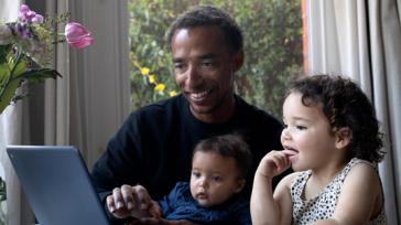 Man with small children looking at a laptop